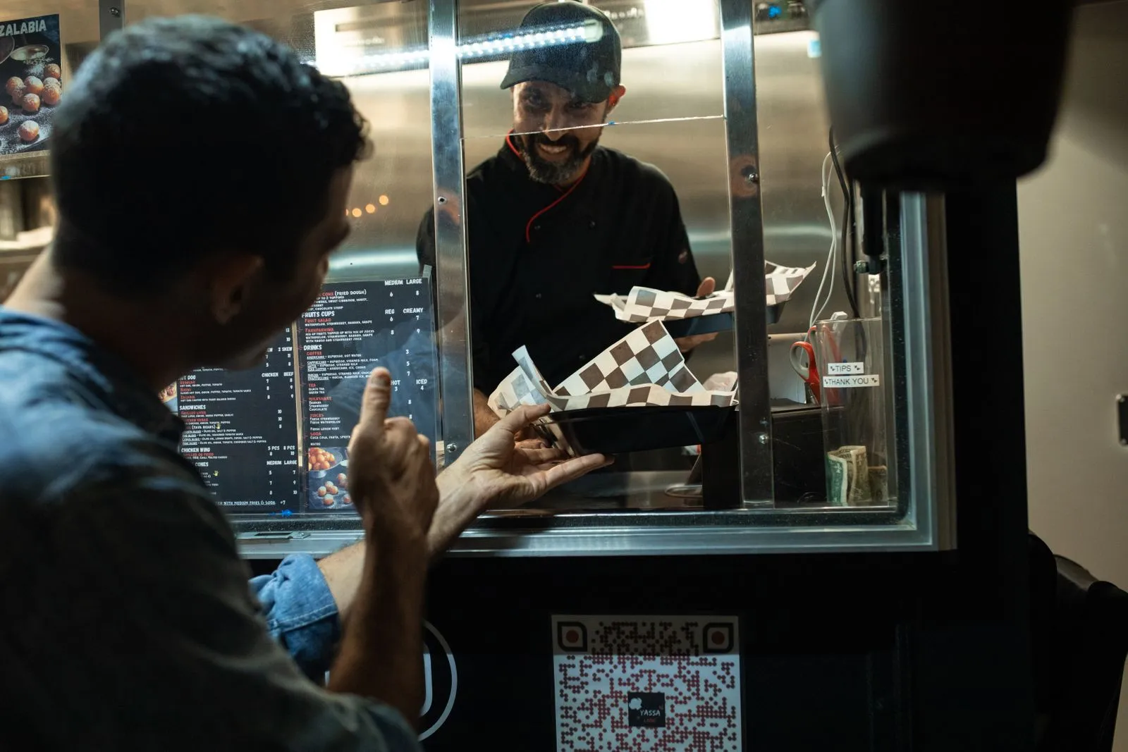 Ein Gast nimmt seine Bestellung an einem Foodtruck entgegen